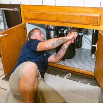 Plumber repairing under-sink pipes